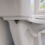Water droplet beneath one toilet tank-to-bowl mounting bolt while the second mounting bolt remains dry